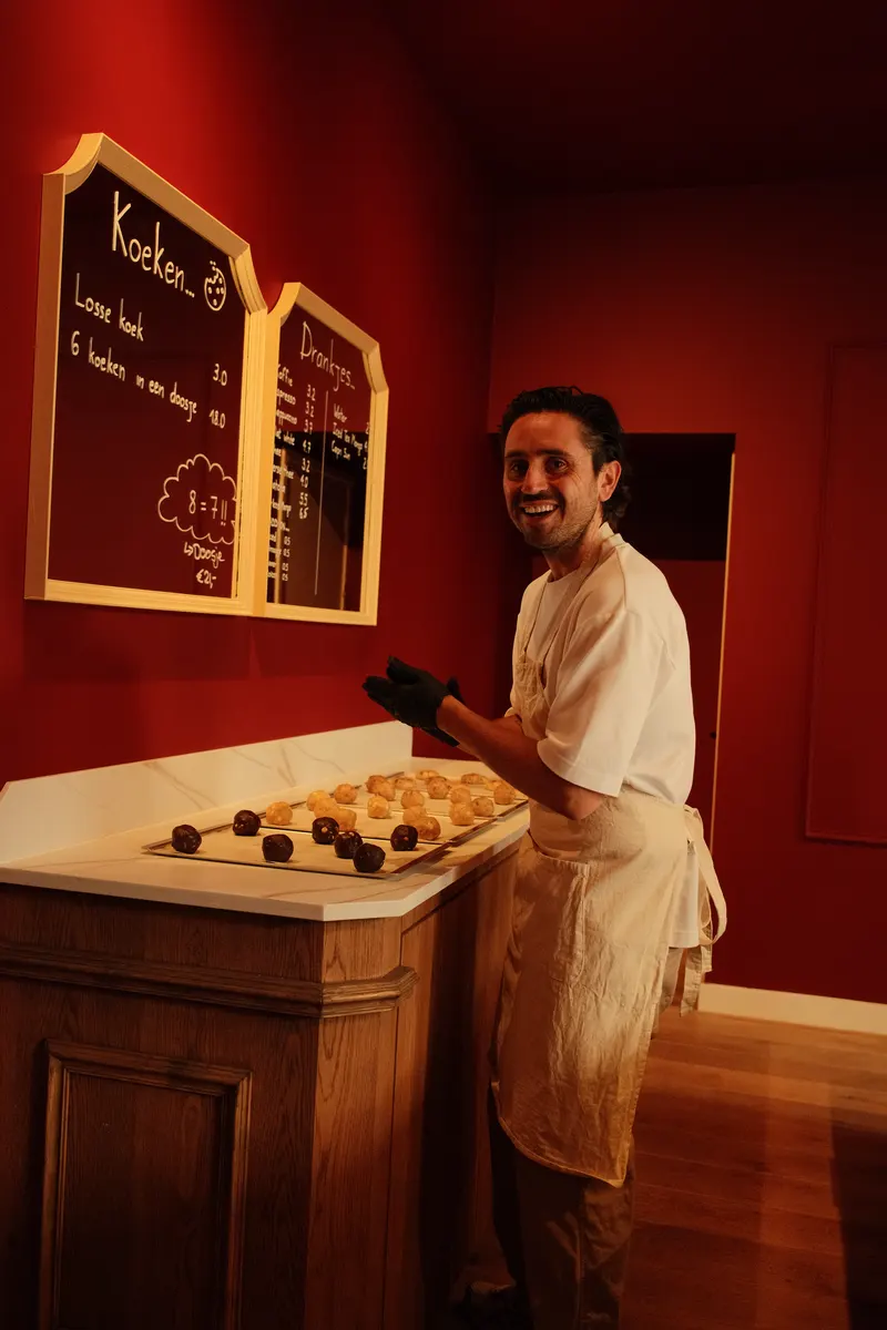 Dami lacht achter de balie naast het krijtbord met het menu