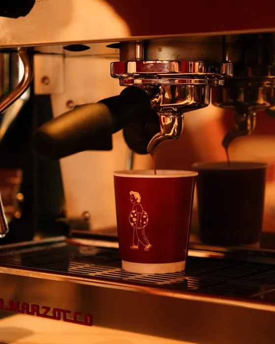 Espresso loopt in een rode beker met het logo